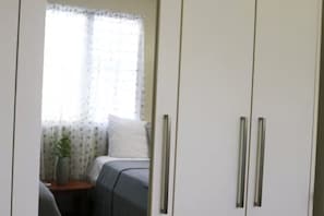 A room with a bed, a small table with a plant, and a window with curtains. - Apartments Pepe's View - A (Bo. Piedras Blancas)