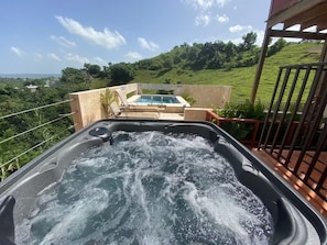 A hot tub with a view of a swimming pool and lush greenery in the background. - Apartments Pepe's View - A (Bo. Piedras Blancas)