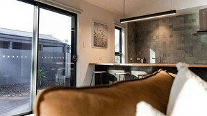 Een moderne keuken met een betegelde achterwand, een eethoek met een tafel en stoelen, en een groot raam met uitzicht op een trein.