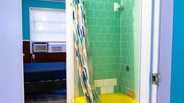 Une chambre avec un lit, une fenêtre et un espace douche carrelé de carreaux verts.