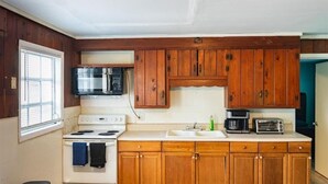 A kitchen with wooden cabinets, a stove, a microwave, and a toaster. - Gpl 2668 3 Bed 2 Bath (Fort Myers)