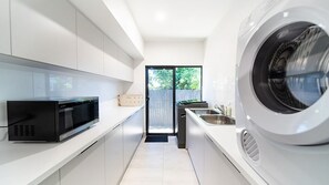 A modern kitchen with a microwave, a washing machine, and a sink. - Golden Tides - Mission Beach (Mission Beach)