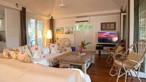 A living room with a sofa, a coffee table, a television, and wicker chairs. - Windjana Wongaling Beach (Wongaling Beach)