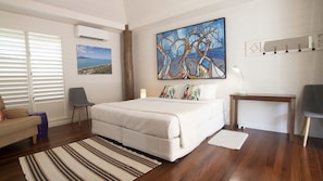 A bedroom with a bed, a chair, a desk, and a painting on the wall. - Windjana Wongaling Beach (Wongaling Beach)