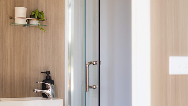 A bathroom with a wooden vanity, a glass shower enclosure, and a hand dryer. - Field and Fleece Farm Stay by Tiny Away (Levels Valley)