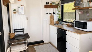 Une cuisine compacte avec des meubles blancs, un plan de travail en bois et un four à micro-ondes encastré.