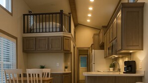 A compact living space with a kitchenette, a dining area with wooden chairs, a sofa, and a coffee table. - Marina View Cottage at key largo (Key Largo)