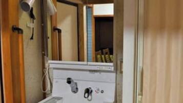 A compact kitchenette with a built-in stove, a sink, and a mirror above the countertop.