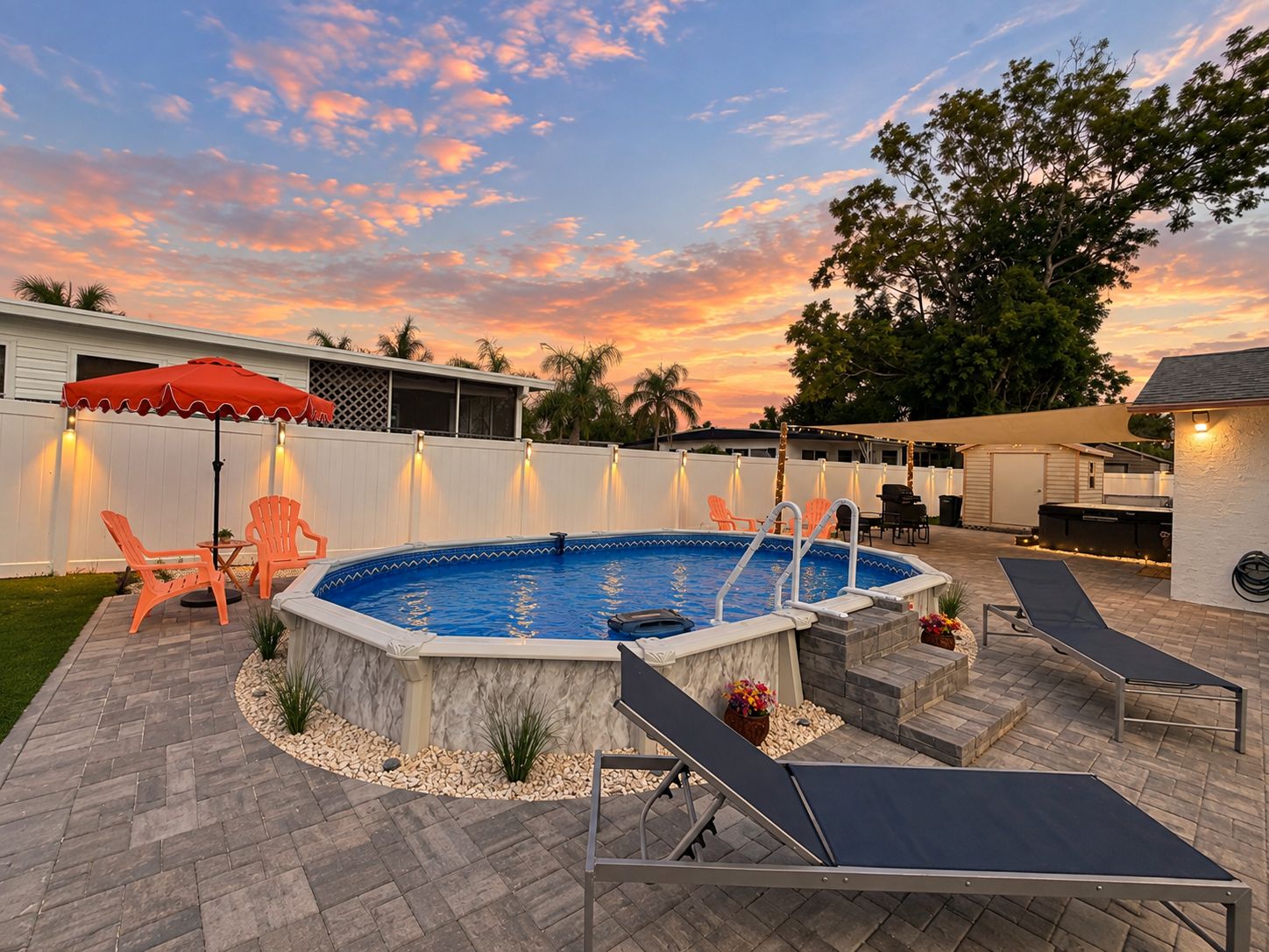 A backyard with a swimming pool, lounge chairs, and a patio area.