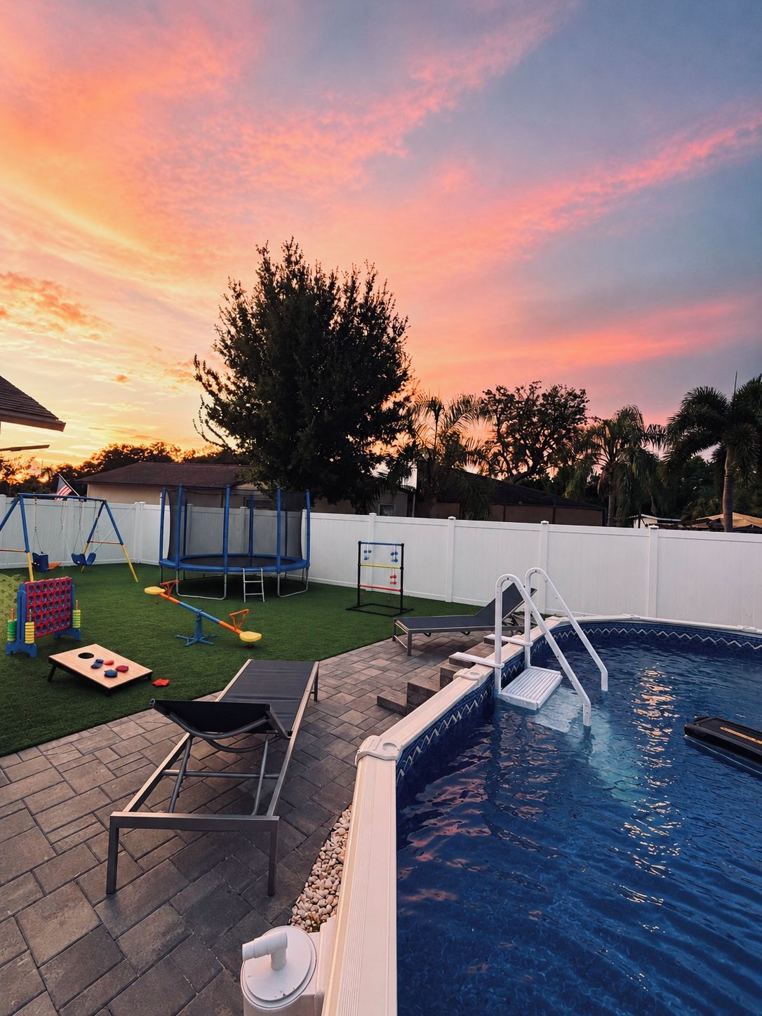 Un jardin avec une piscine, un trampoline et une balançoire.
