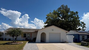 A residential house with a garage, a paved driveway, and a well-maintained lawn. - Sunny Oasis by Tarpon - Heated Pool, Hot Tub & Playground (Holiday)