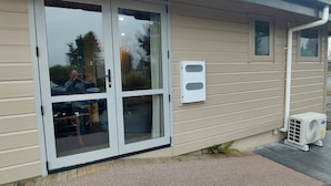 Un bâtiment doté d’une porte coulissante en verre, d’une petite fenêtre et d’un appareil de climatisation sur le côté.