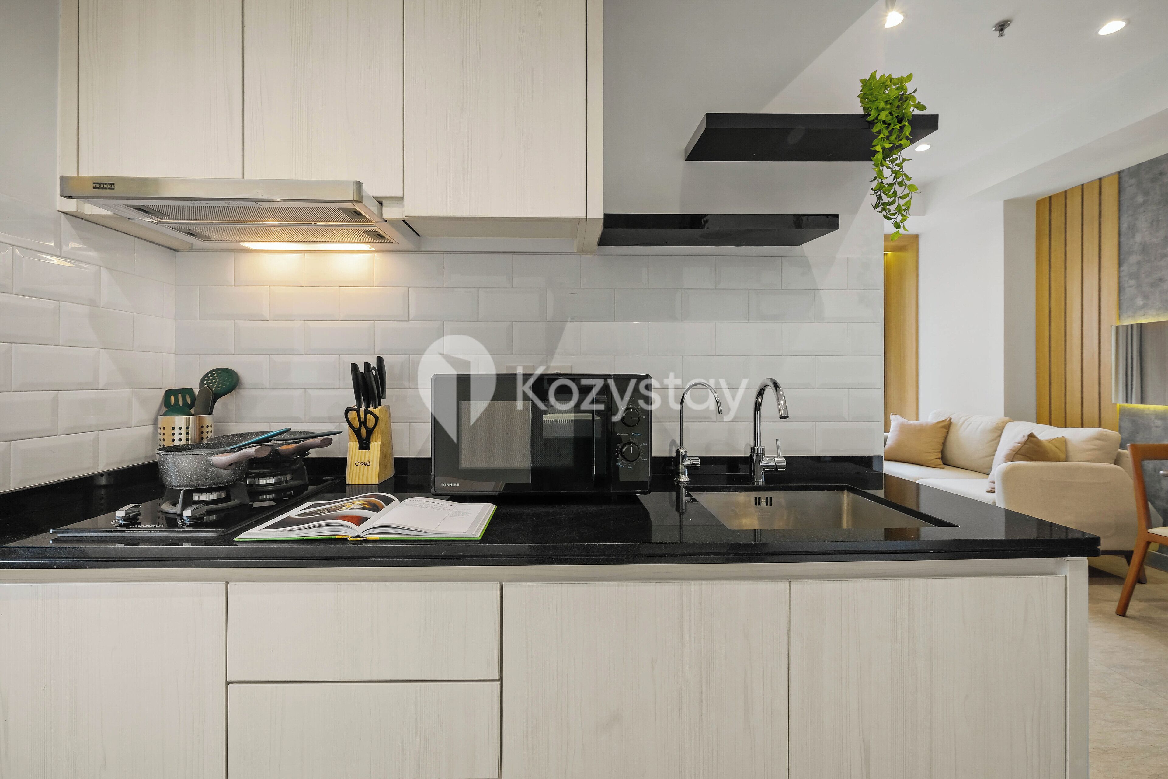 A modern kitchen with white cabinetry, a black countertop, and a built-in stove.