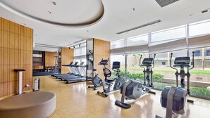 A modern gym with treadmills, elliptical machines, and a rowing machine. - Sorven by Kozystay - BSD (Pagedangan)