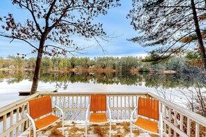 A wooden deck with three chairs overlooking a calm lake surrounded by trees. - Dock! Dog-Friendly Lakefront Gem in Southern Maine (Waterboro)