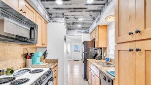 A kitchen with wooden cabinets, a stainless steel refrigerator, a microwave, and a stove. - Island Breeze Condo on the Beach (Englewood)