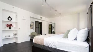 A modern bedroom with a large bed, a small side table, and a desk with a chair. - Double King Studio 800sqft (Los Angeles)