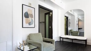 A modern living room with a light green armchair, a glass coffee table, and a framed abstract painting on the wall. - Double King Studio 800sqft (Los Angeles)