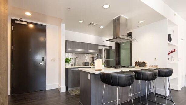 A modern kitchen with a central island, bar stools, and a dark wooden floor. - Double King Studio 800sqft (Los Angeles)