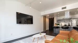 A modern living room with a large flat-screen TV, a white coffee table, and a brown sofa. - Double King Studio 800sqft (Los Angeles)