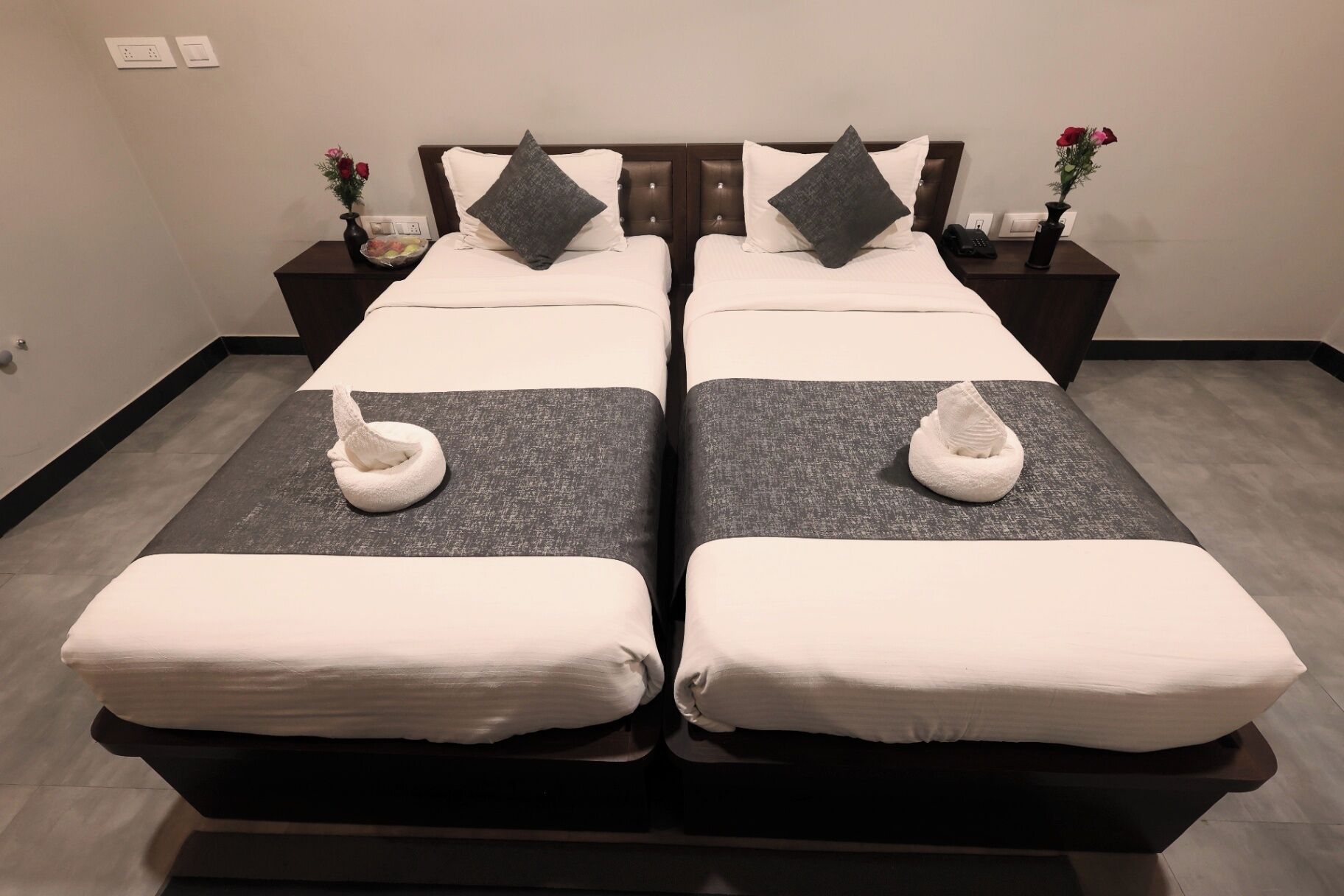 Una cama doble con dos almohadas, una mesita de noche con un florero y una toalla en cada cama.