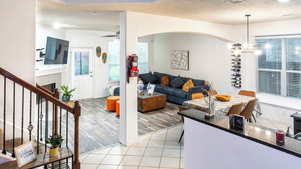 A modern living area with a sofa, coffee table, and dining table. There is a staircase with a welcome sign. - Marvelous 5-bedroom house with AC in charming Tomball (Tomball)