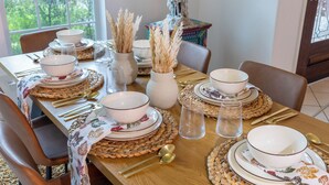 A dining table set with white bowls, plates, and cutlery, surrounded by woven placemats and decorative vases. - Marvelous 5-bedroom house with AC in charming Tomball (Tomball)