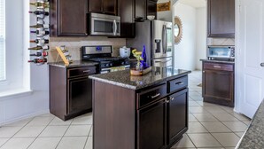 A modern kitchen with dark wood cabinets, stainless steel appliances, and a wine rack on the wall. - Marvelous 5-bedroom house with AC in charming Tomball (Tomball)
