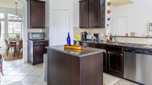 A modern kitchen with dark wood cabinets, stainless steel appliances, and a central island. - Marvelous 5-bedroom house with AC in charming Tomball (Tomball)