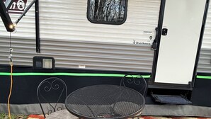 Un camper con un'area pranzo che include un tavolo rotondo e due sedie, un piccolo oblò e una porta.