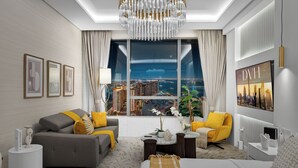 A modern hotel room with a city view, a grey sofa, yellow armchairs, a round coffee table, and a large bed. - Palm Tower Palm Jumeirah By DVH Luxe (Dubai)