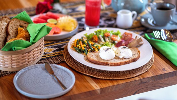 A breakfast setting with toast, eggs, vegetables, and a fruit bowl. - Govala Ubud Villa & Spa (Tegallalang)