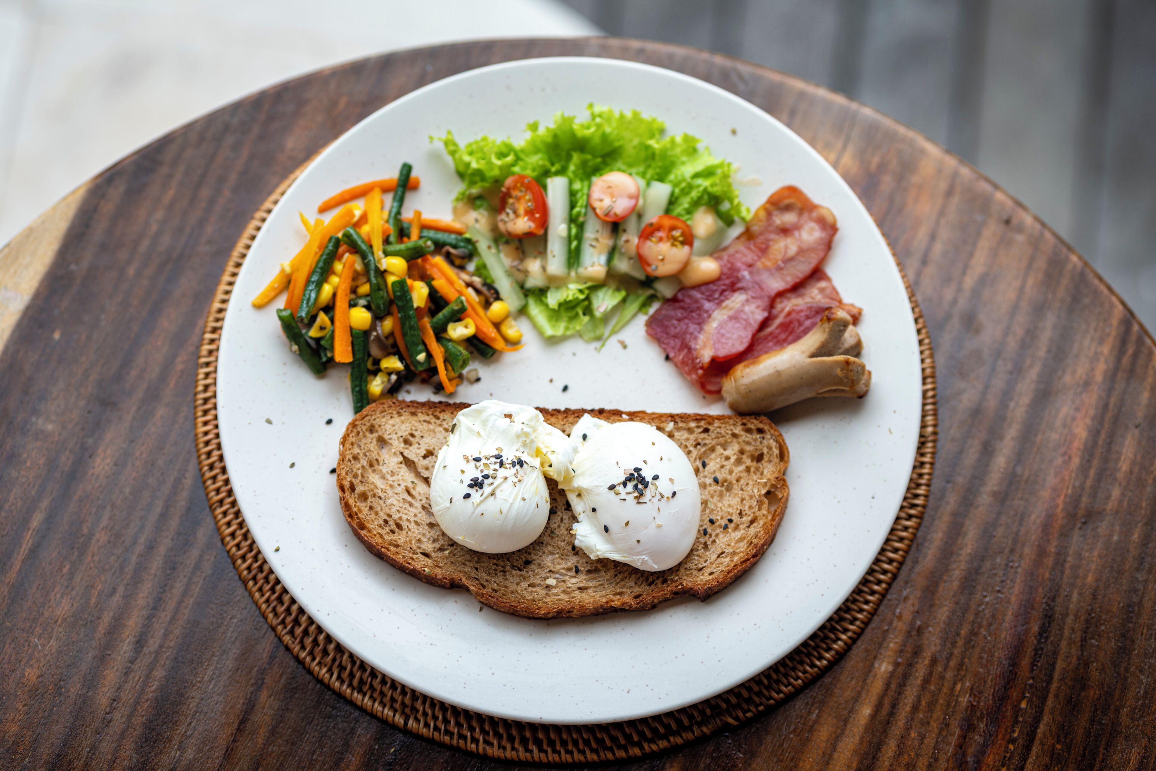 Een bord met salade, spek en eieren op toast.