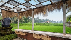 A covered outdoor seating area with a view of green rice fields. - Govala Ubud Villa & Spa (Tegallalang)