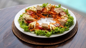 A round plate of salad with lettuce, carrots, tomatoes, and bread on a wooden table. - Govala Ubud Villa & Spa (Tegallalang)