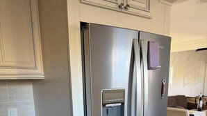 A stainless steel refrigerator with a water dispenser, wooden cabinets, and a tiled backsplash. - Fabulous 5-bedroom chalet in charming Wilmington perfect for groups (Wilmington)