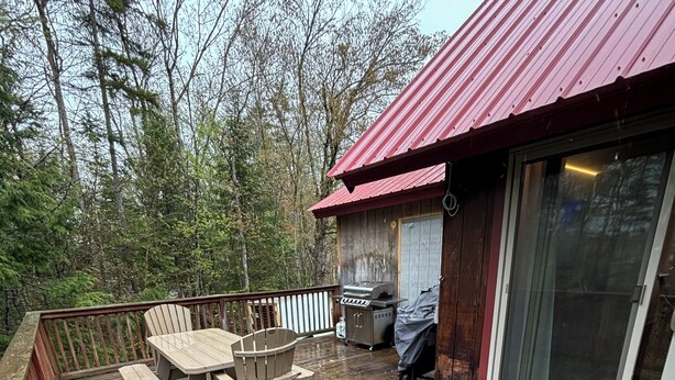 A wooden deck with a table and chairs, a grill, and a glass door leading to a covered area. - Fabulous 5-bedroom chalet in charming Wilmington perfect for groups (Wilmington)