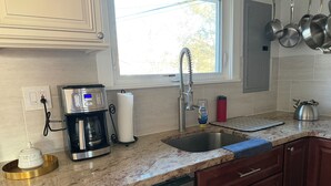 A kitchen with a coffee maker, a sink, a dish drying rack, a kettle, and a red water bottle. - Fabulous 5-bedroom chalet in charming Wilmington perfect for groups (Wilmington)
