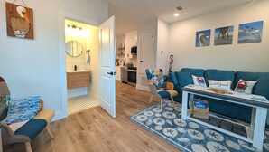 Uma sala de estar aconchegante com um sofá azul, uma mesa de centro e piso de madeira.