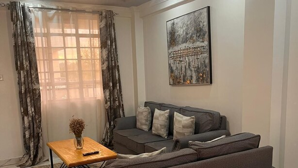 Un soggiorno moderno con un divano grigio, un tavolino in legno e un quadro appeso al muro.