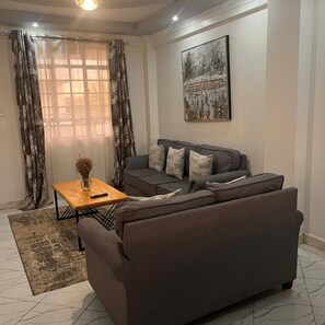 Una sala de estar moderna con un sofá gris, una mesa de centro de madera y un cuadro en la pared.