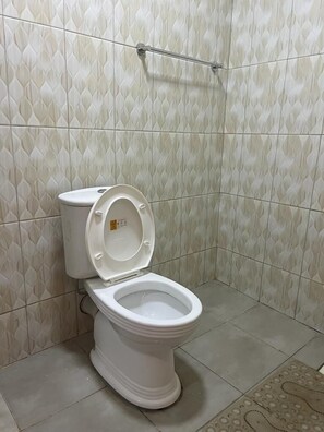 A bathroom with a toilet, patterned tiles, and a handrail. - Koselig Homes califonia Plaza Nanyuki (Nanyuki)