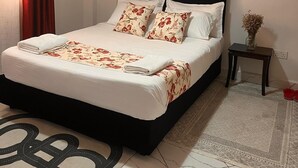 Un letto rifatto con lenzuola a motivi floreali, una testiera scura e un quadro raffigurante alberi al muro.