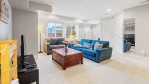 Ein Wohnzimmer mit einem blauen Sofa, einem Holztisch und einem Fernseher auf einem Schrank.