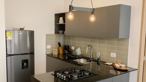 Eine moderne Küche mit grauen Schränken, einem Edelstahlkühlschrank, einem Gasherd und zwei Barhocker.