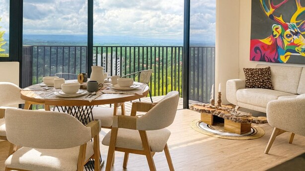 Ein modernes Wohnzimmer mit Essbereich, großen Fenstern und einem Balkon mit Blick.