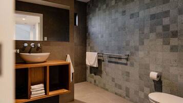 A modern bathroom with a large sink, mirror, and towel rack.