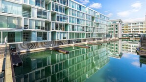 A modern building with multiple balconies and a reflective pool. - QV Stays Waterfront Retreat 2 Bed 2 Bath (Auckland)