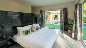 Un dormitorio moderno con una cama grande, un cabecero oscuro y vistas a una piscina a través de un ventanal corredero.