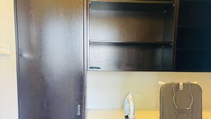 Habitación compacta y moderna con un armario oscuro, una tabla de planchar pequeña y una encimera blanca.